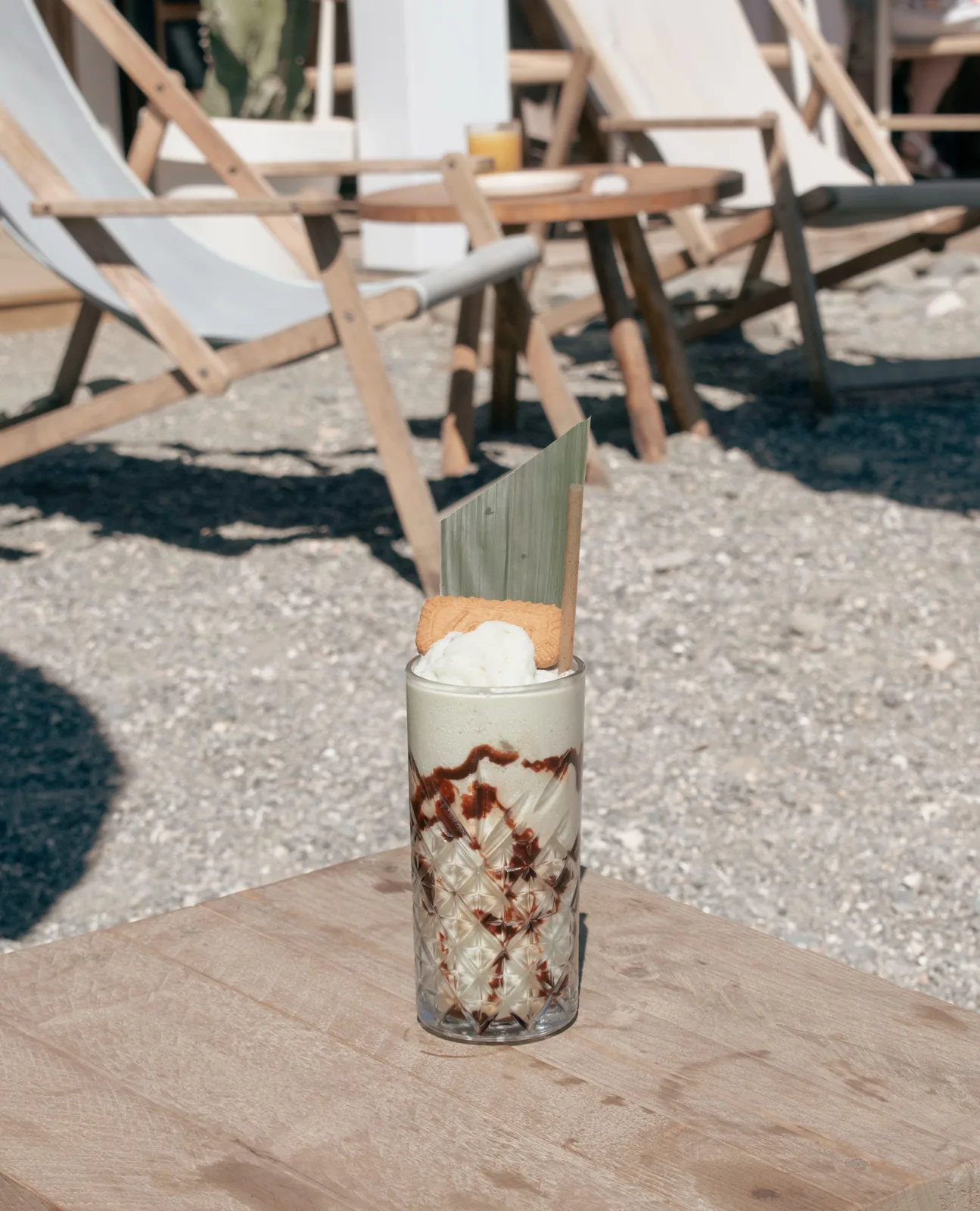 Milkshake Pistachio Dream con pistacho, chocolate, miel y avellanas sobre una mesa en la arena