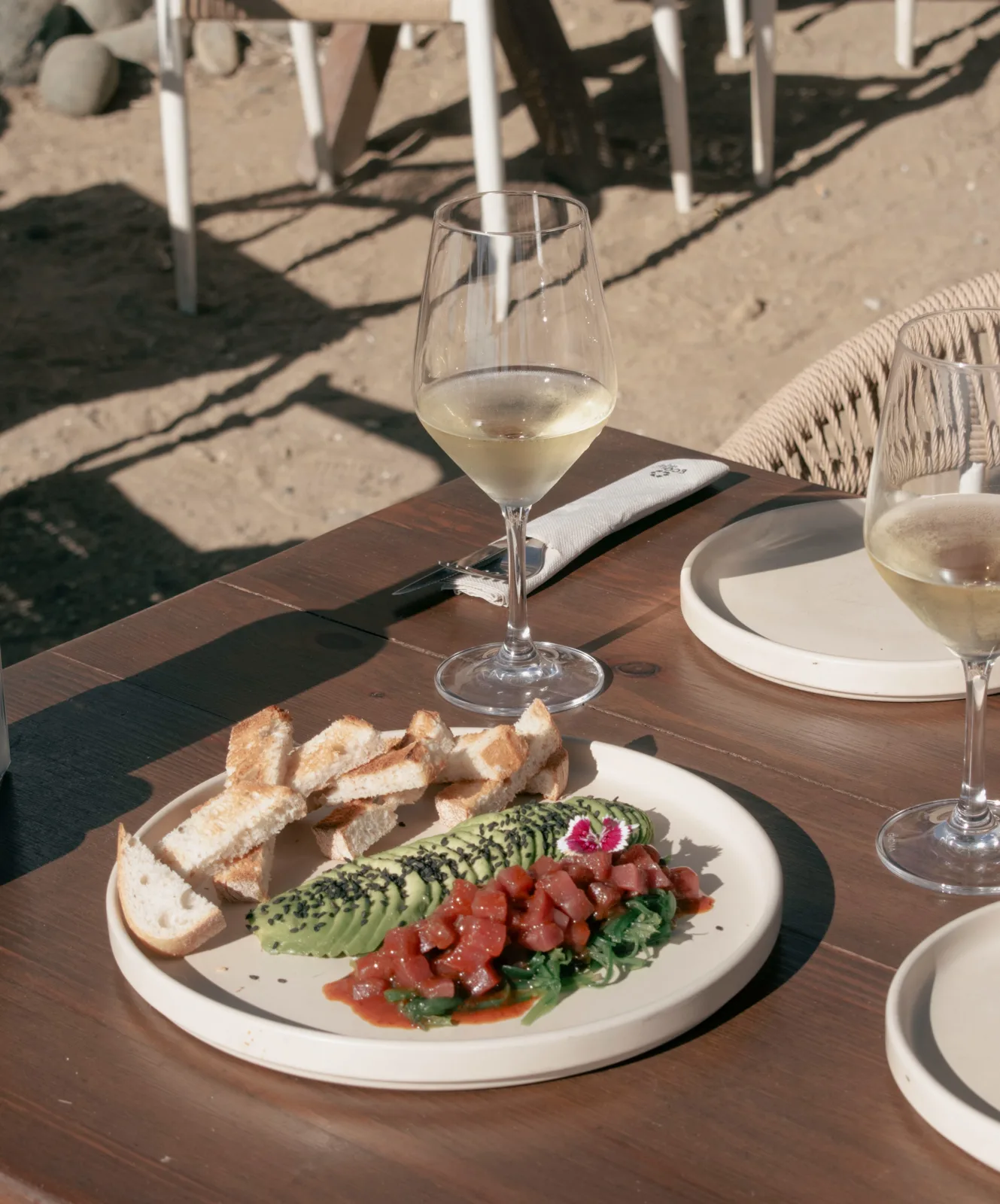 Tartar de atún de Almadraba con aguacate y kimchi, pan tostado y copas de vino blanco en la terraza